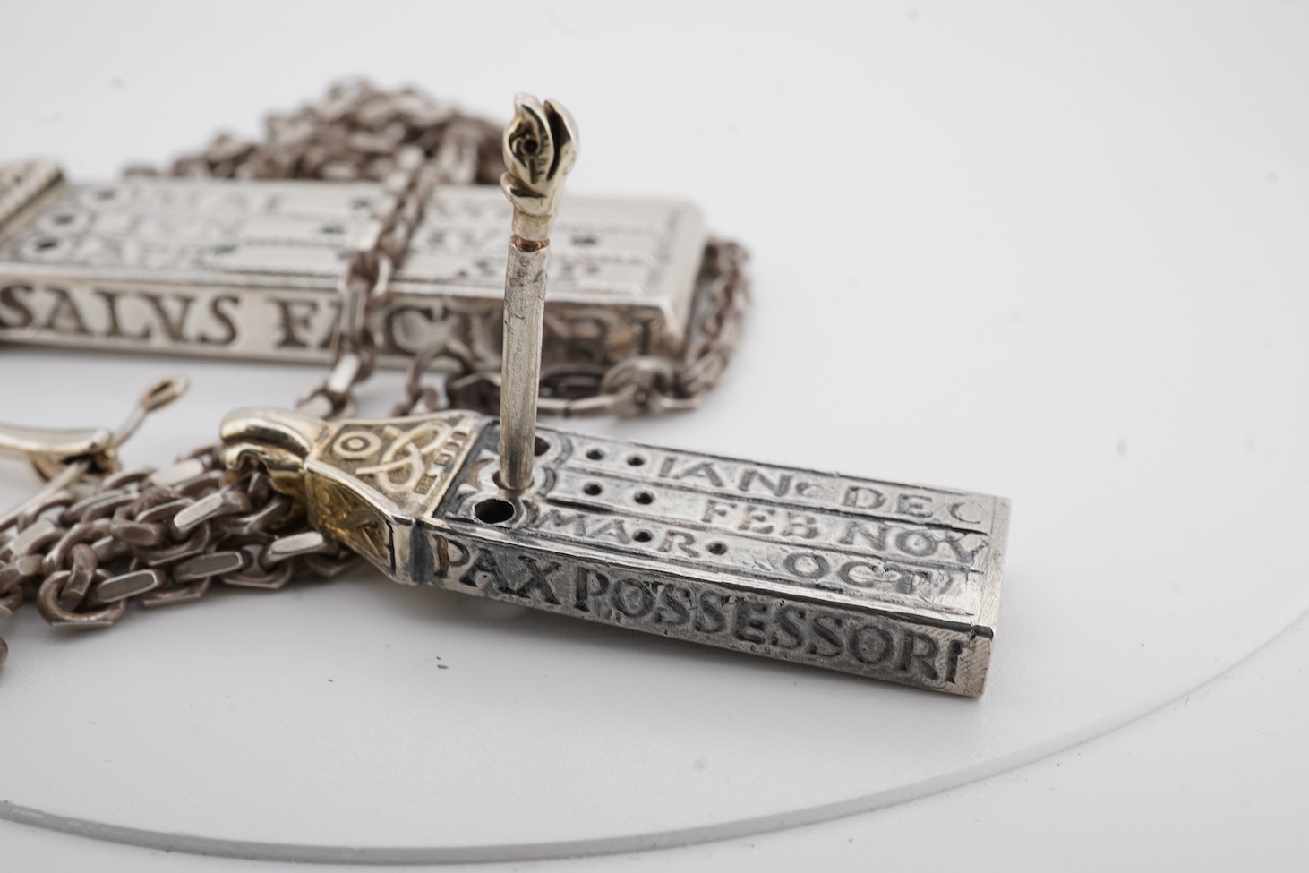 Two modern parcel gilt silver replicas of the Canterbury Pocket Sundial, the larger inset with small emeralds?, maker GF, London, 1975, the smaller later, maker DB, London, 1987, both suspended from a chain.
